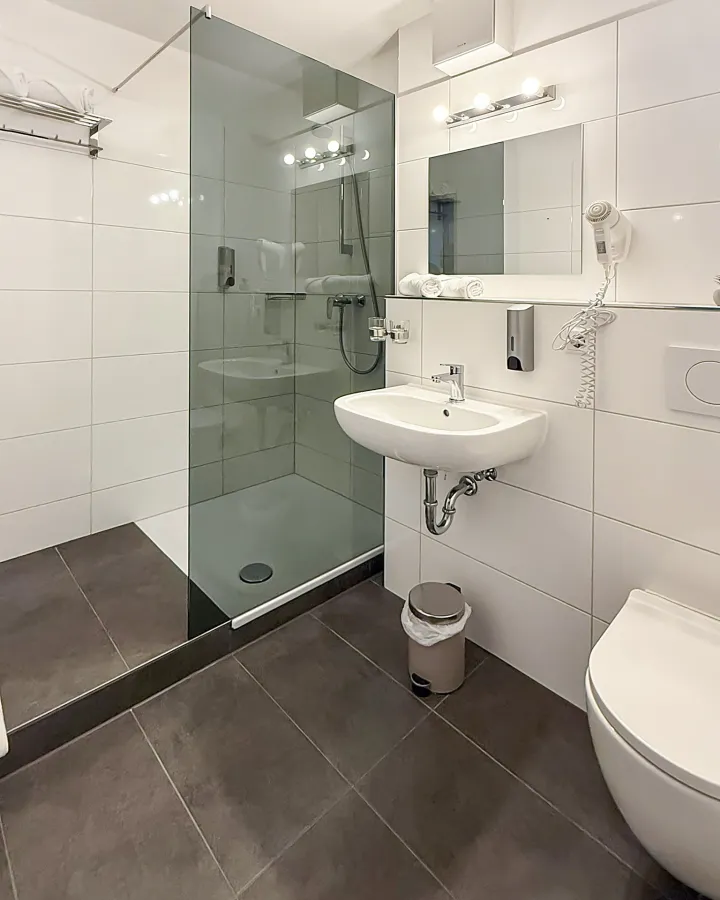 Badezimmer mit Glasdusche, Waschbecken und WC