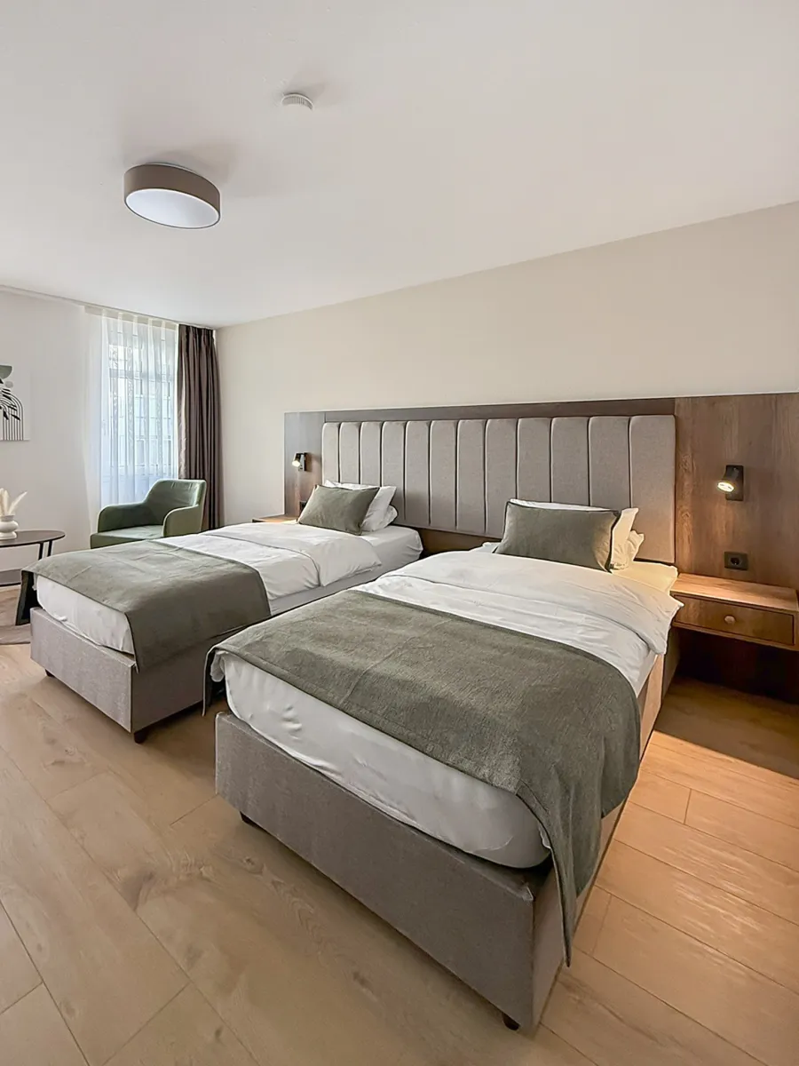 Hotelzimmer mit zwei Betten, Polsterkopfteil und Holzwand