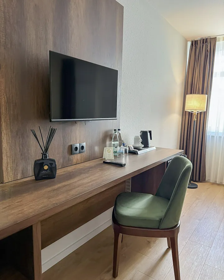 Schreibtisch mit Fernseher, Leselampe und grünem Stuhl