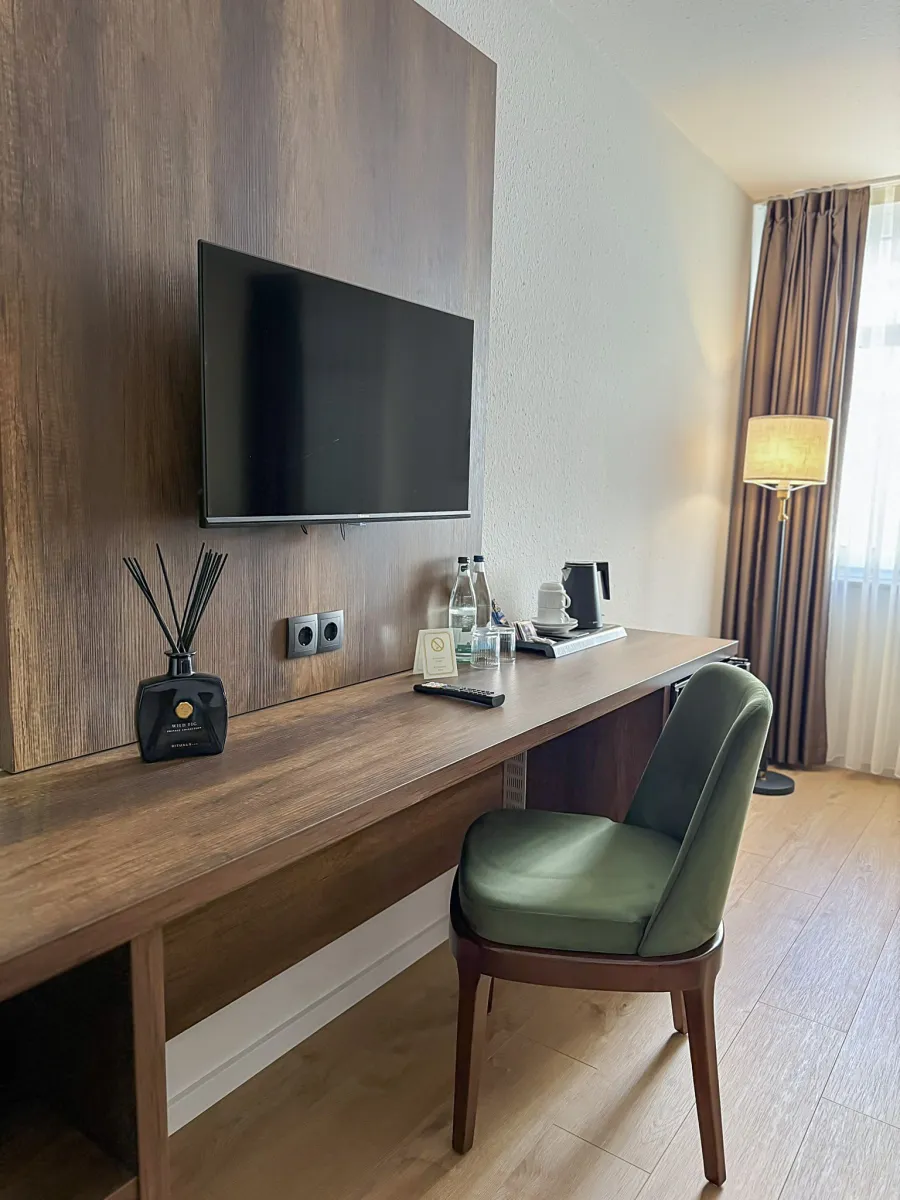 Schreibtisch mit Fernseher, Leselampe und grünem Stuhl